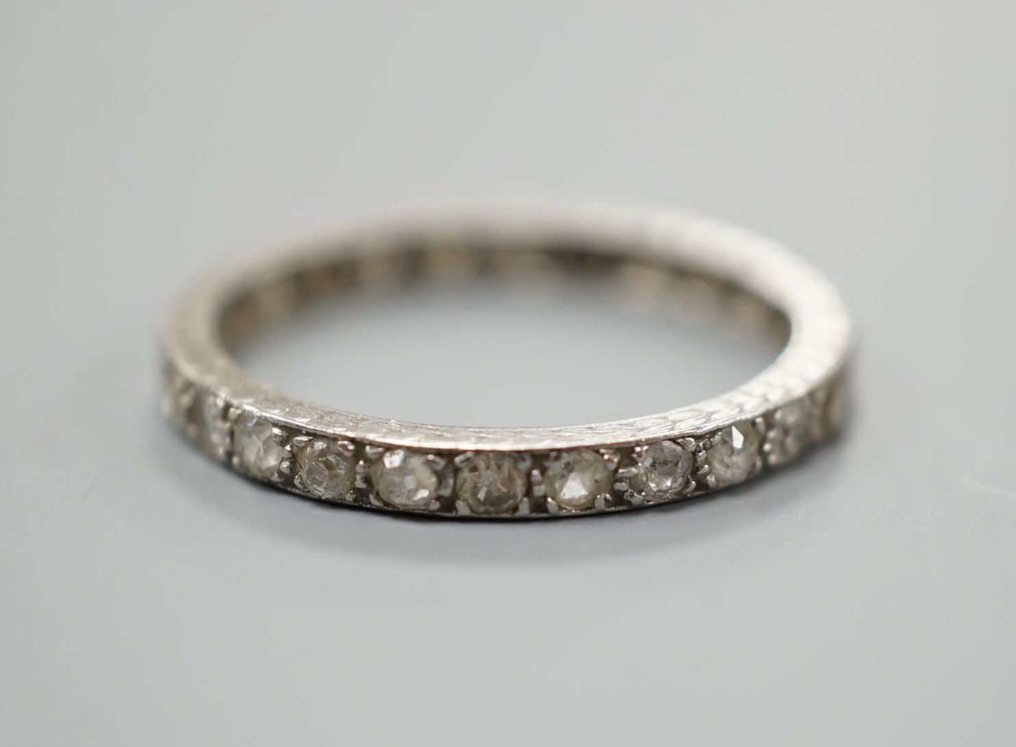A white metal and diamond chip set full eternity ring, size M, gross weight 2.1 grams.